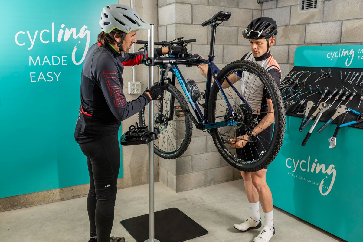 Dos personas ajustan una bicicleta en taller con texto cycling made easy en pared.