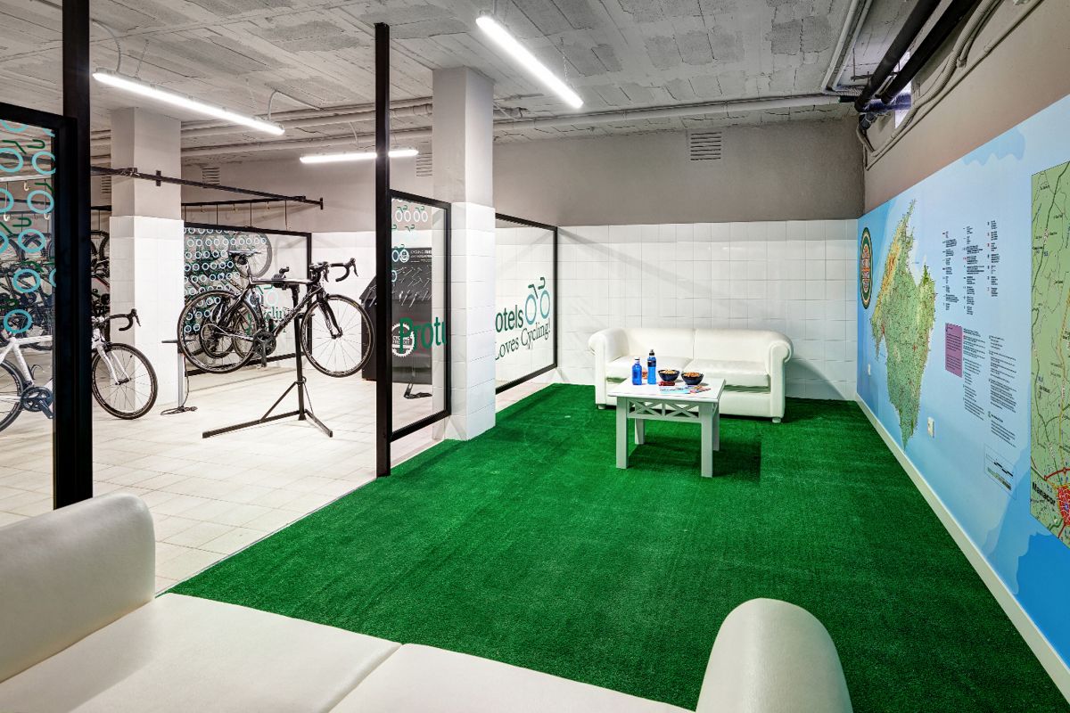 Zona de descanso y taller de bicicletas en hotel de Tenerife, con sofás, mapas y bicicletas.