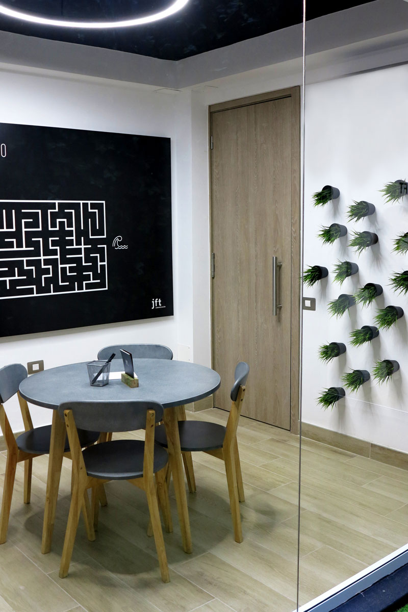 Mesa redonda con sillas, tablero con laberinto y plantas en pared en sala de Tenerife.