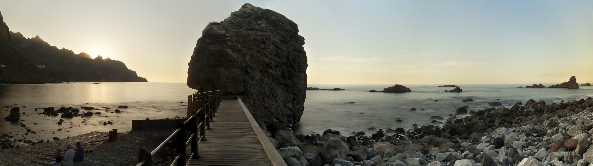 Atardecer en la costa de Tenerife con roca y pasarela de madera.