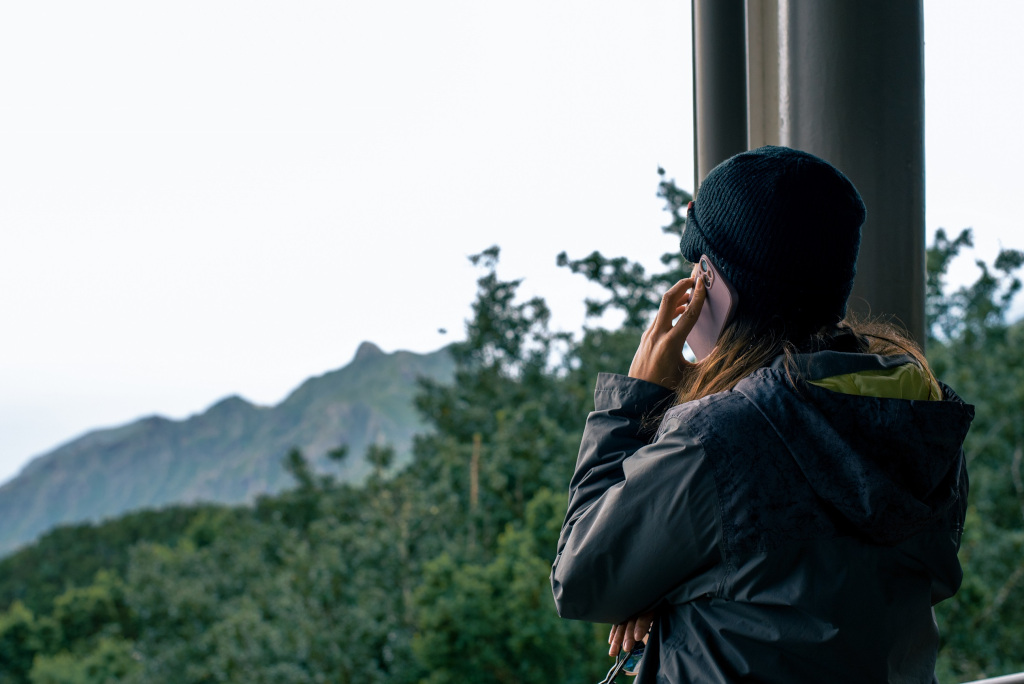 Persona llamando por teléfono con paisaje montañoso en Tenerife al fondo.