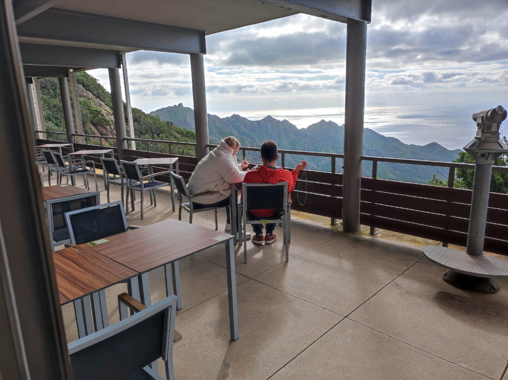 Personas sentadas en terraza con vista a las montañas y el mar en Tenerife.