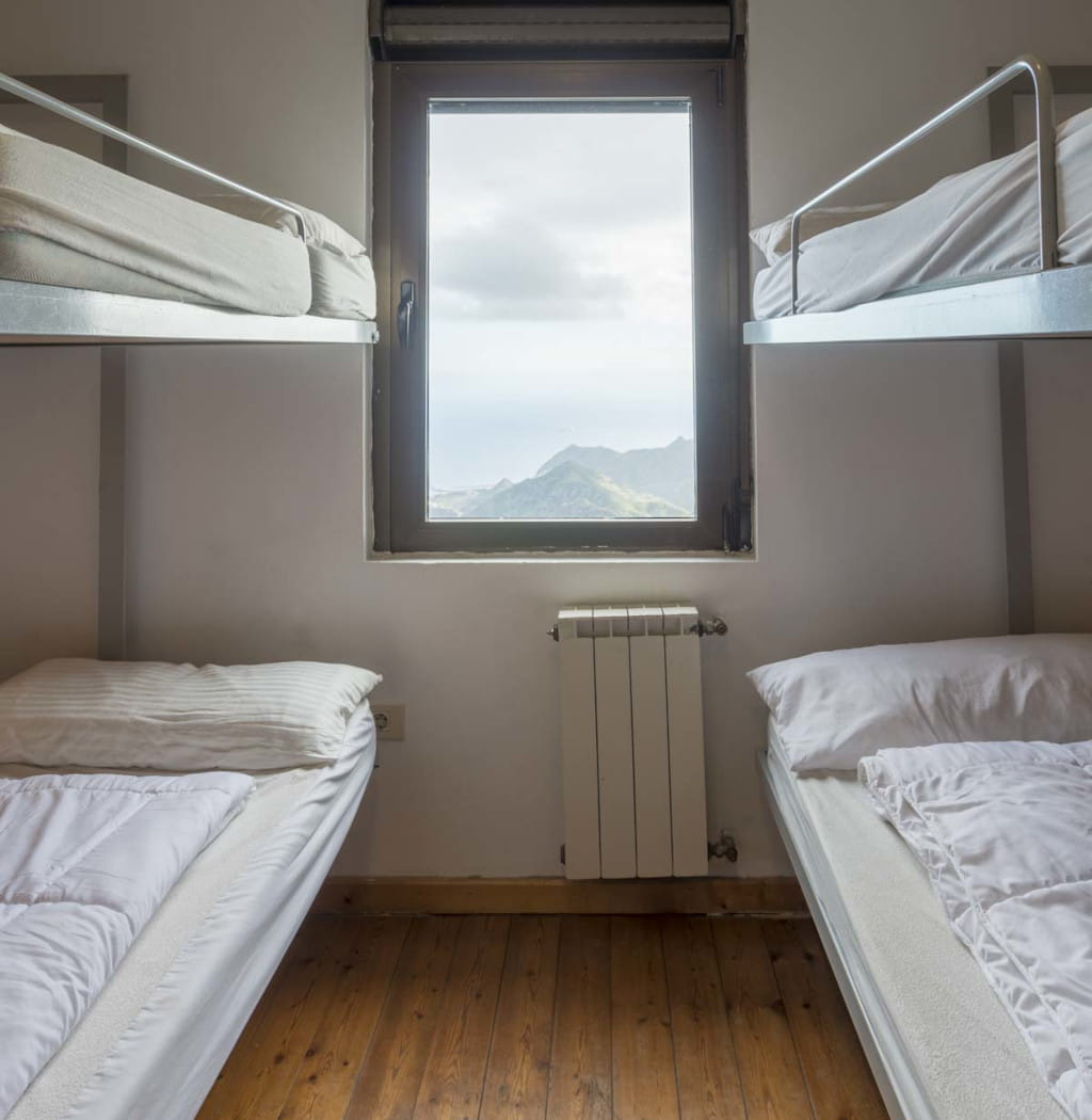 Literas en un dormitorio con vista a montañas de Tenerife por la ventana.