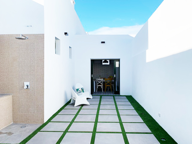Patio moderno con sillas blancas y camino de baldosas en Tenerife.