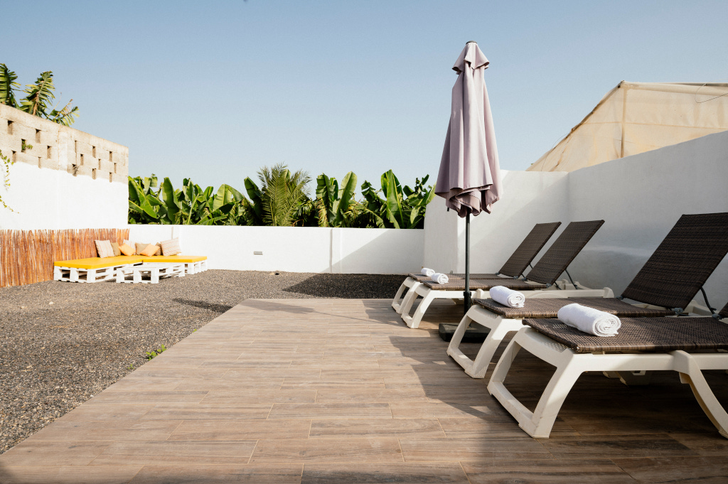 Tumbonas y sombrilla en una terraza con vista a plataneras en Tenerife.