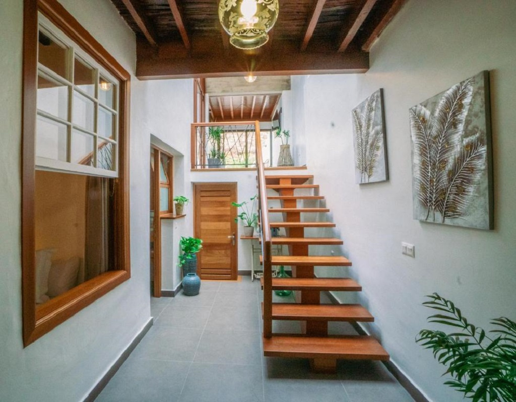 Escalera de madera en un pasillo con plantas y cuadros en Tenerife.