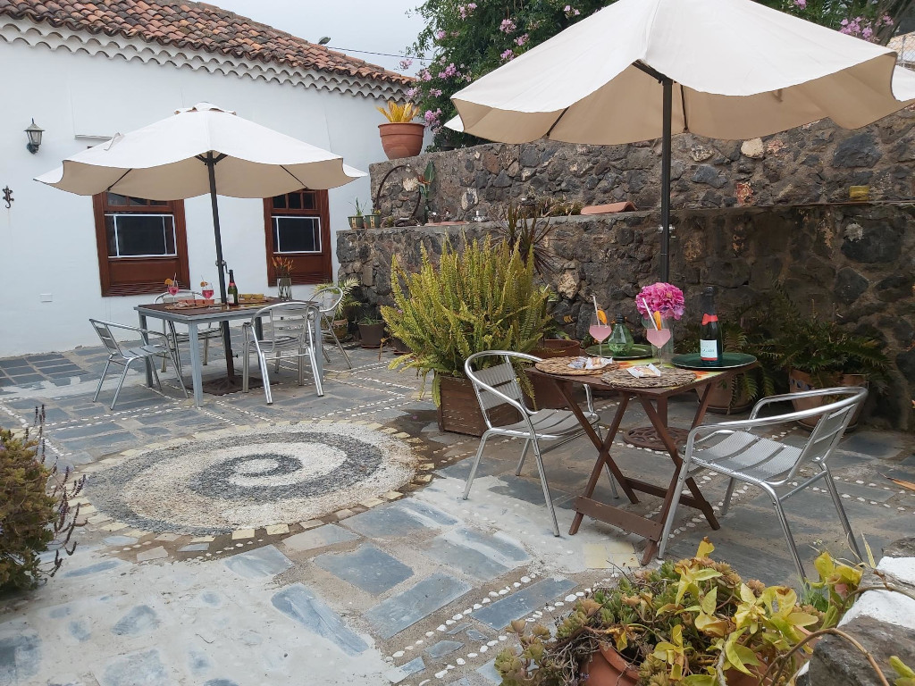 Patio exterior en Tenerife con mesas, sillas y sombrillas.