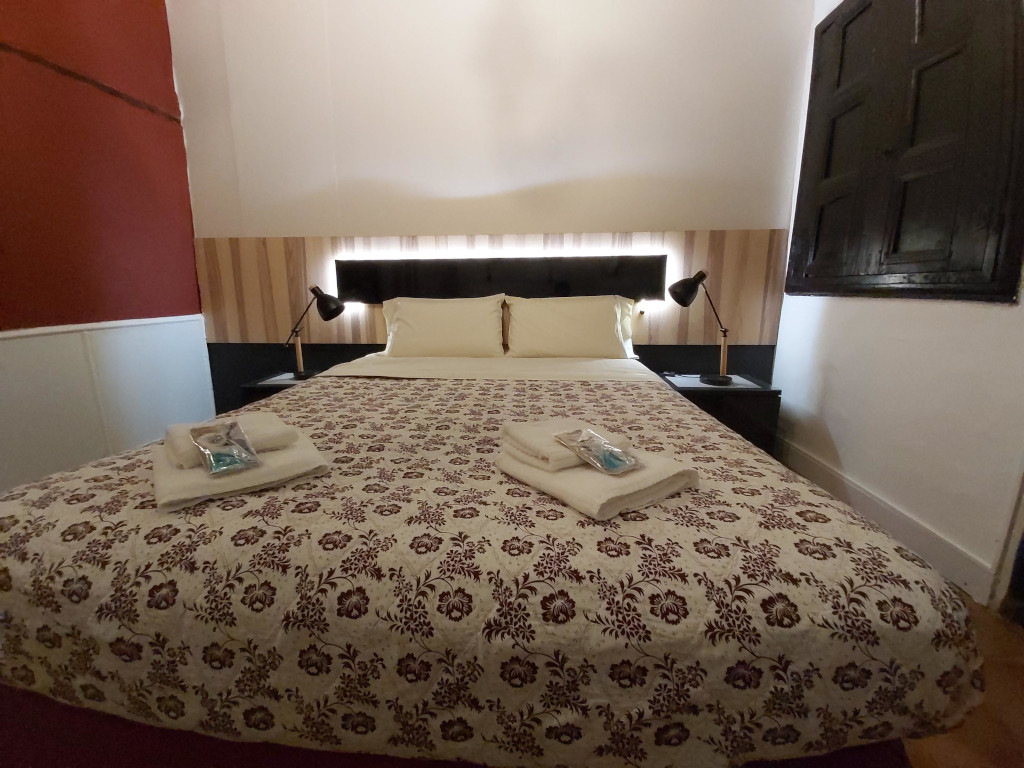 Cama doble con colcha floral, lámparas y toallas en habitación de hotel en Tenerife.