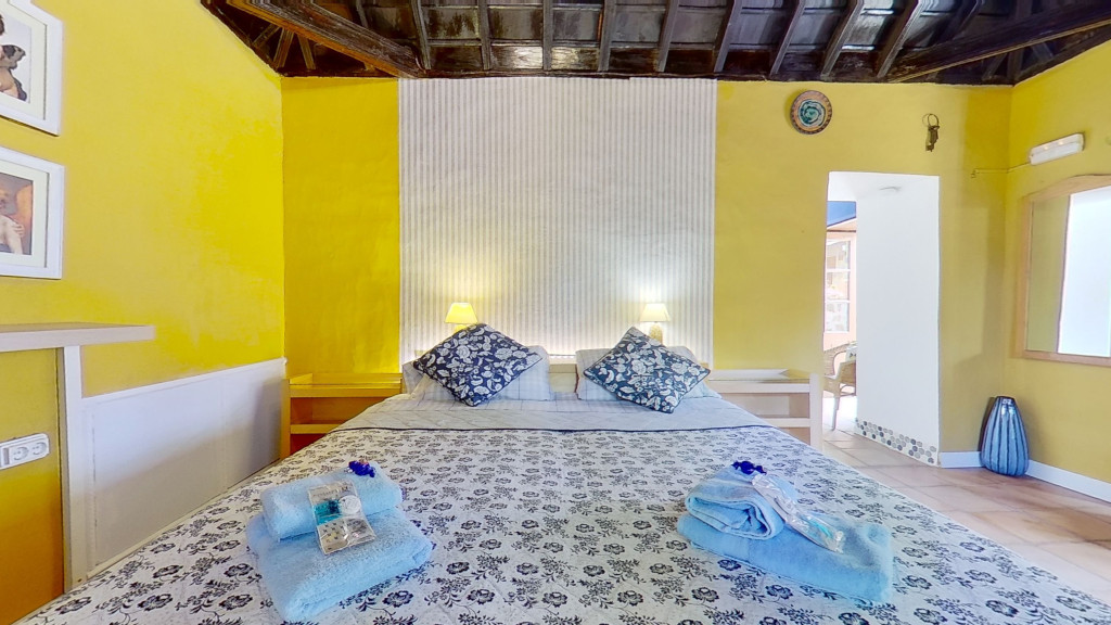 Habitación con cama doble y paredes amarillas en Tenerife, con toallas sobre la cama.