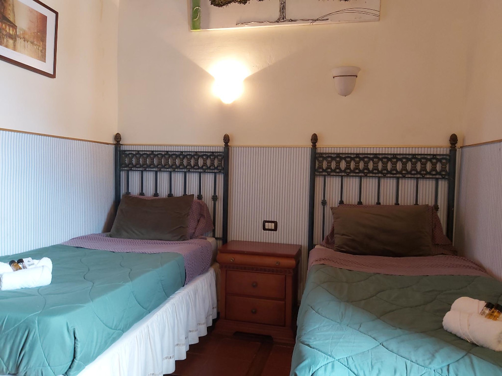 Dos camas individuales con cabeceras de metal y mesita de noche en habitación de Tenerife.