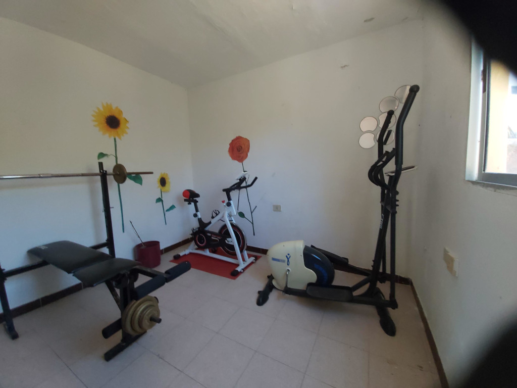 Gimnasio en Tenerife con bicicleta estática y pesas.
