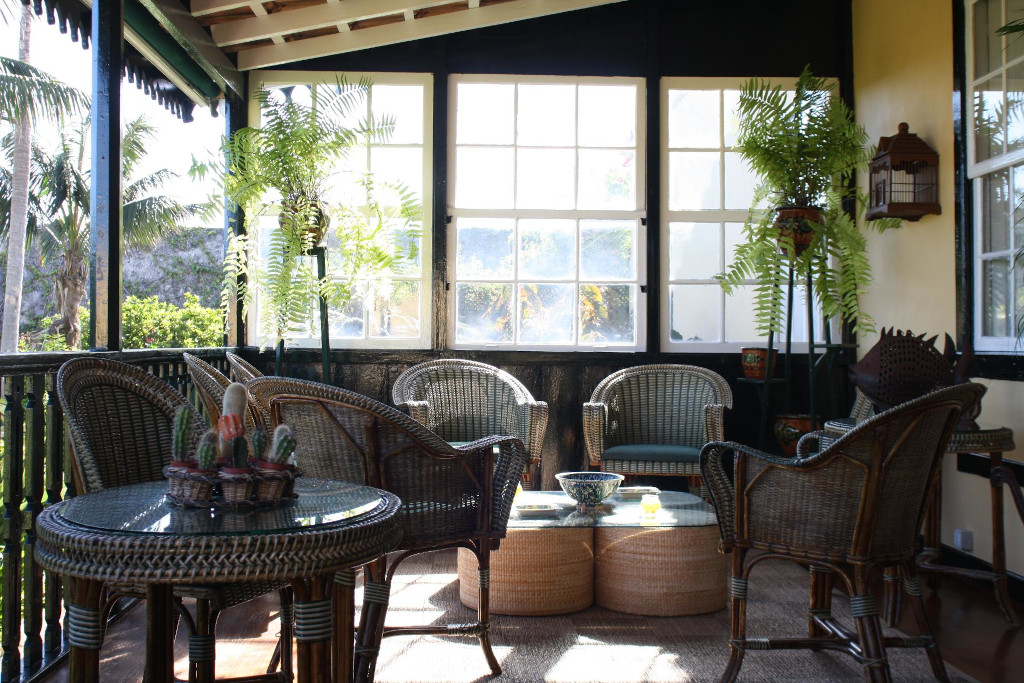 Terraza con muebles de mimbre, plantas y mesa de cristal en Tenerife.