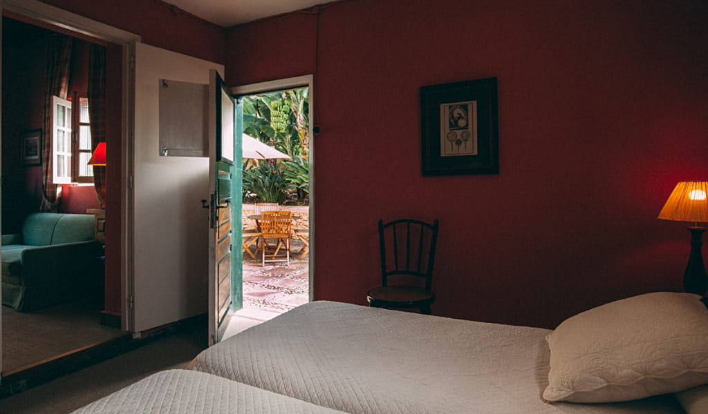 Dormitorio con cama doble y acceso a patio con muebles de exterior en Tenerife.