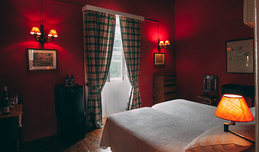 Habitación doble con lámparas de pared y cortinas a cuadros en hotel de Tenerife.