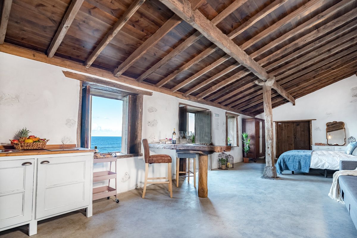 Habitación rústica con techo de madera, vista al mar y cama en Tenerife.