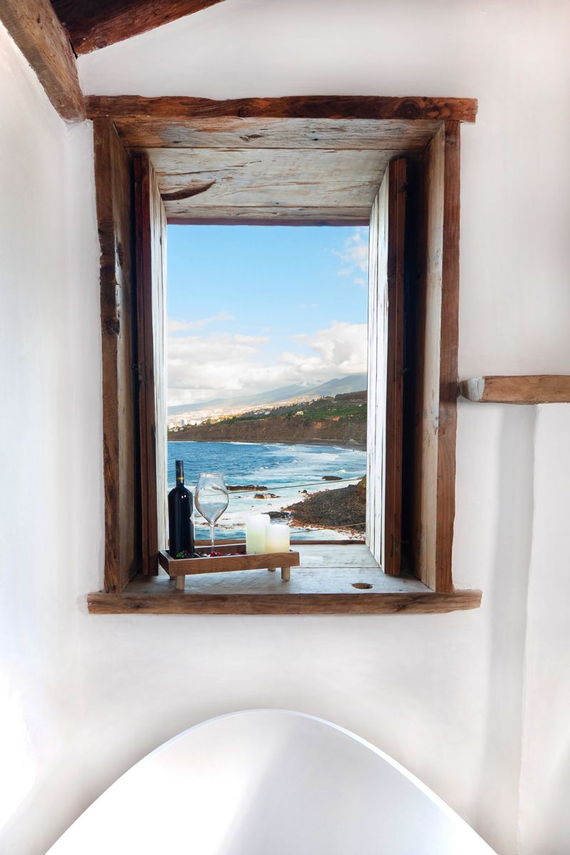Ventana con vista al mar en Tenerife, botella de vino y copas en el alféizar.