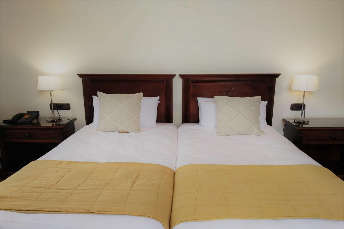 Cama doble con cabecero de madera y mesas de noche en hotel de Tenerife.
