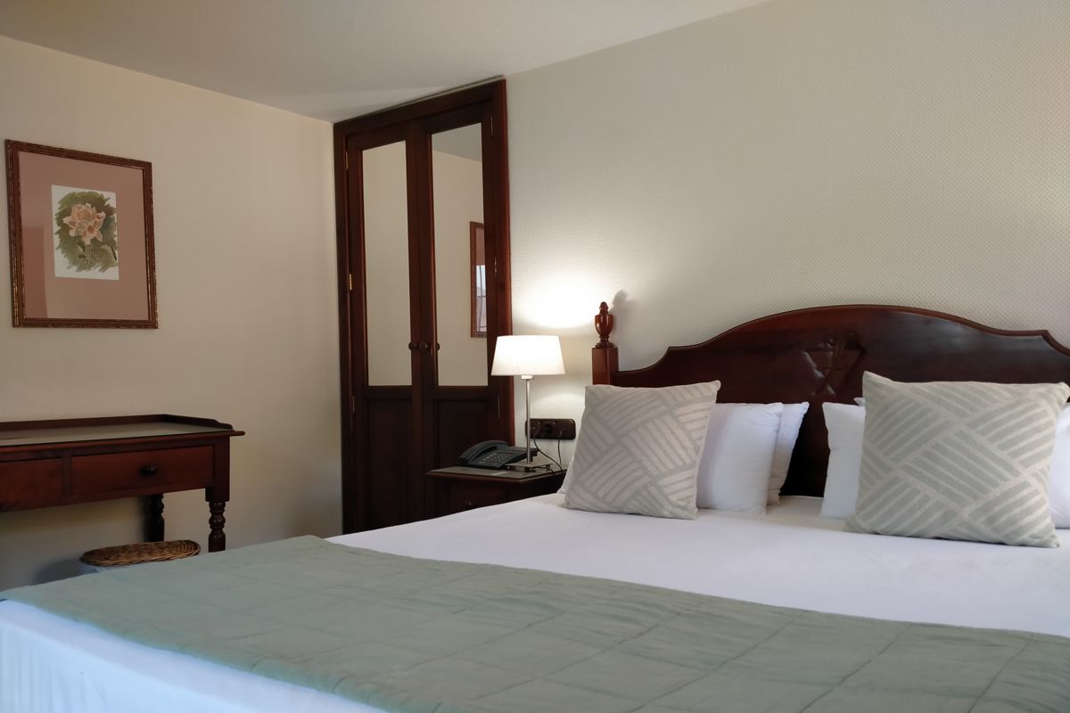 Cama doble con cojines y lámpara en habitación de hotel en Tenerife.