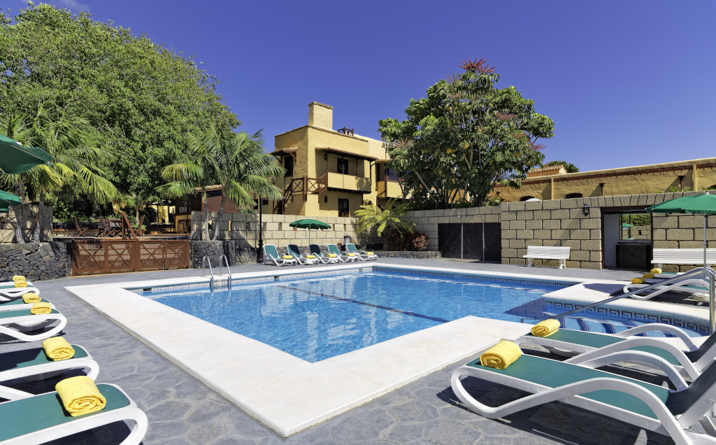 Piscina rodeada de tumbonas y árboles en un hotel de Tenerife.