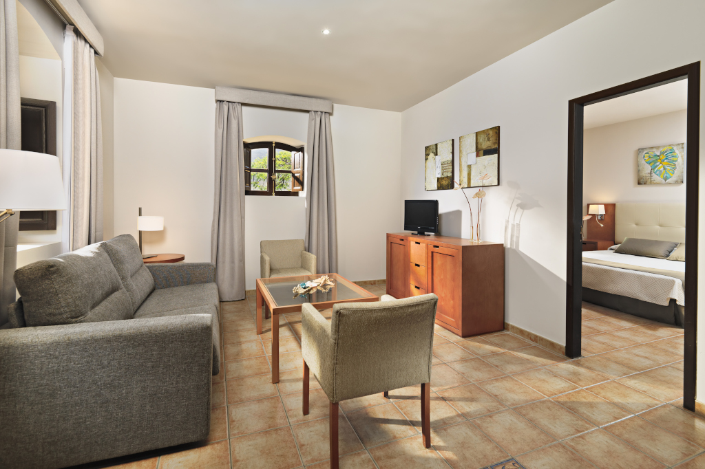 Sala de estar en apartamento en Tenerife con sofá, mesa y televisión.