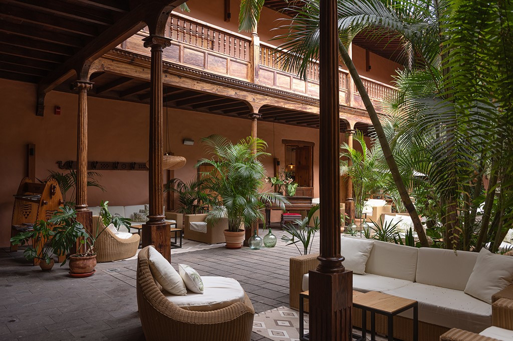 Patio interior con muebles de ratán y plantas en un hotel de Tenerife.