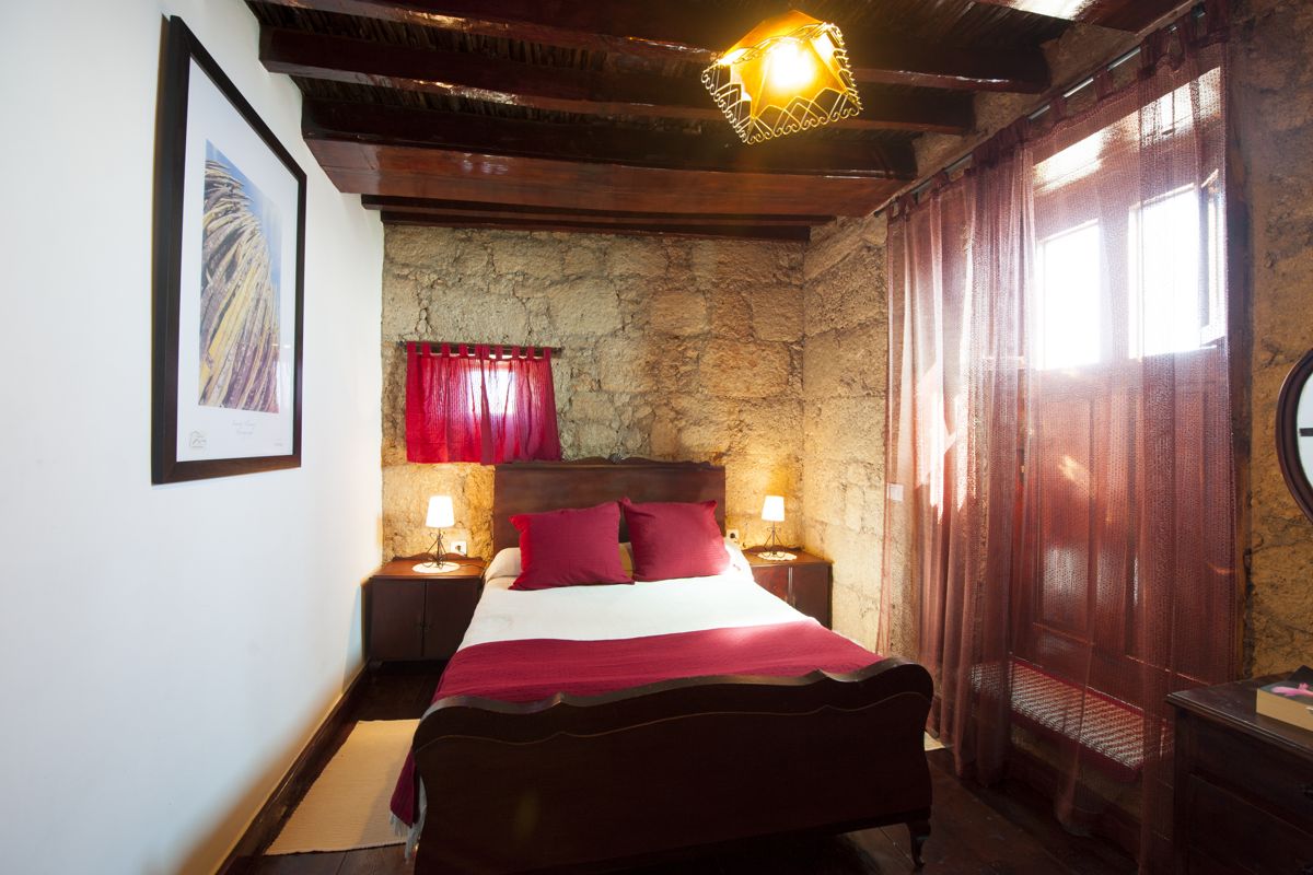 Habitación rústica con cama doble y paredes de piedra en Tenerife.