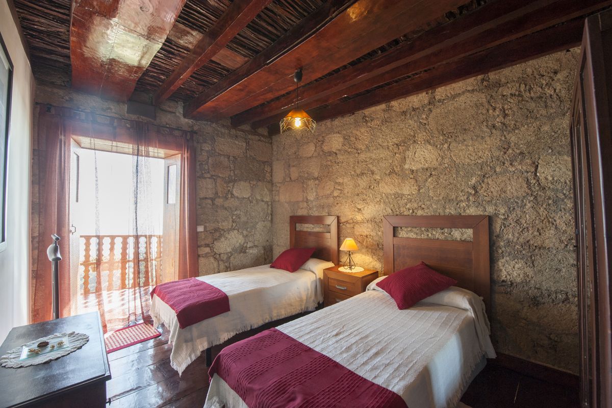 Habitación con dos camas individuales y pared de piedra en Tenerife.