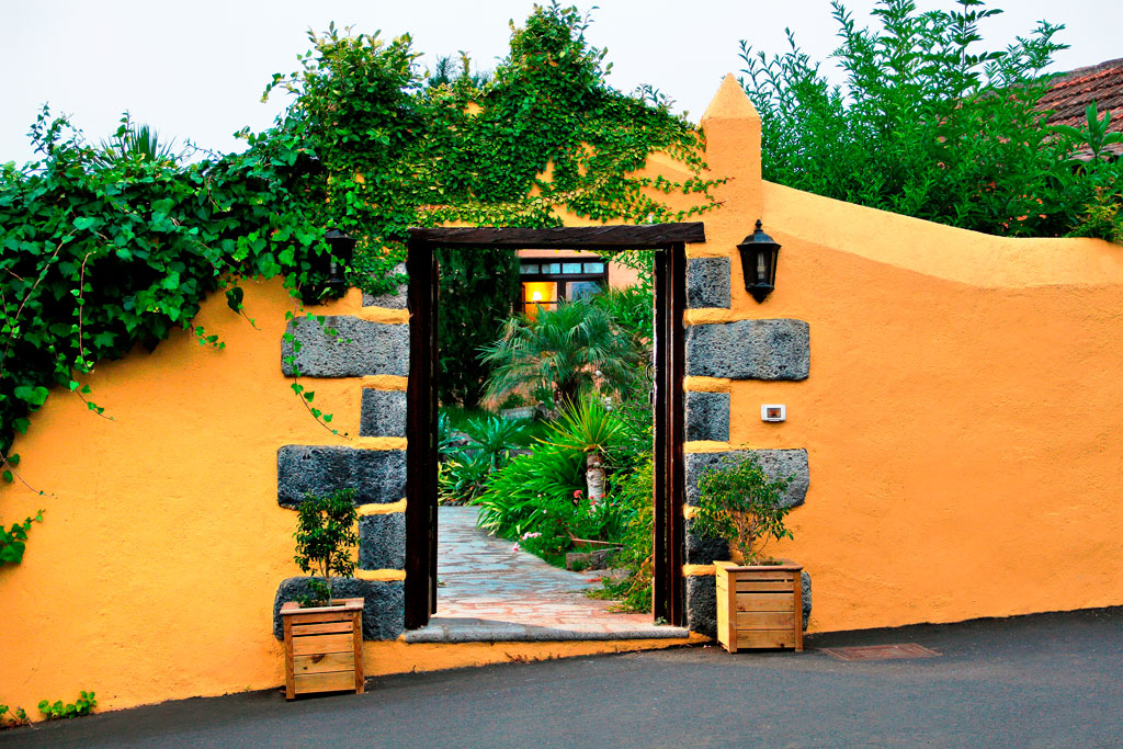 Entrada con plantas y pared amarilla adornada, típica de Tenerife.