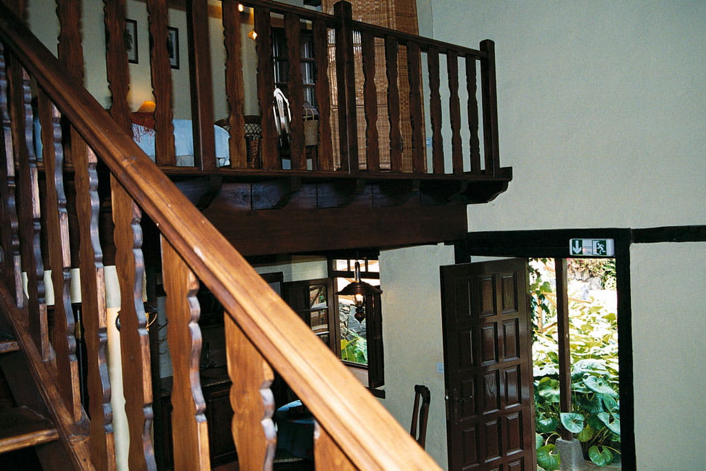 Escalera de madera en casa rural en Tenerife con salida de emergencia señalizada.