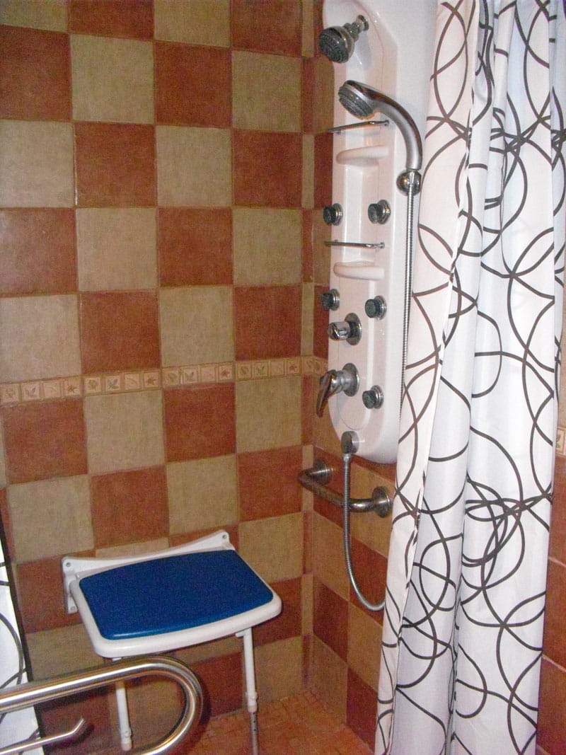 Ducha accesible con asiento y barras de apoyo en un baño de Tenerife.