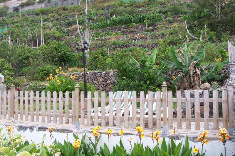 Jardín con terraza y sillas rodeado de plantas y flores en un entorno rural de Tenerife.