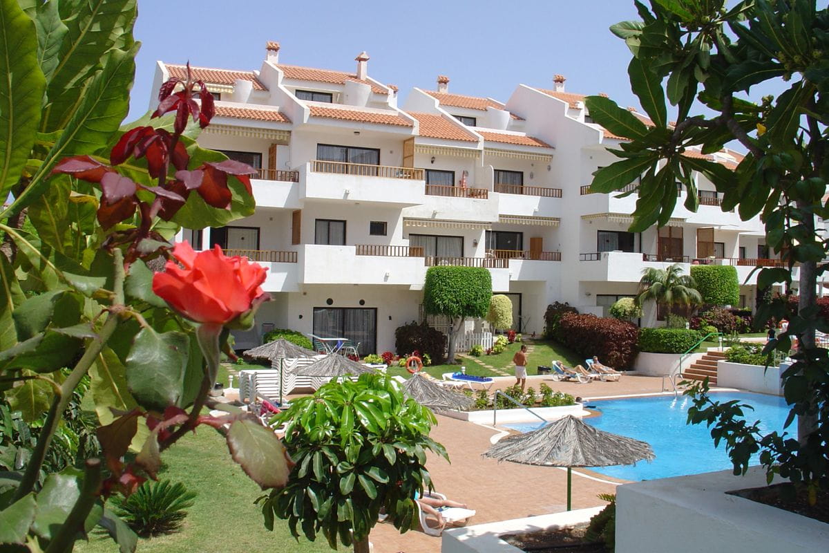 Complejo de apartamentos con piscina y jardines en Tenerife, rodeado de naturaleza.