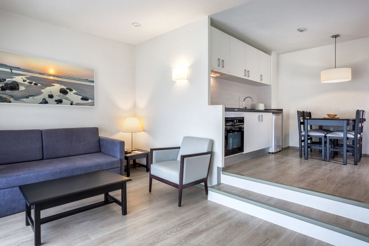 Sala de estar con sofá, mesa de centro, cocina equipada y mesa de comedor en Tenerife.