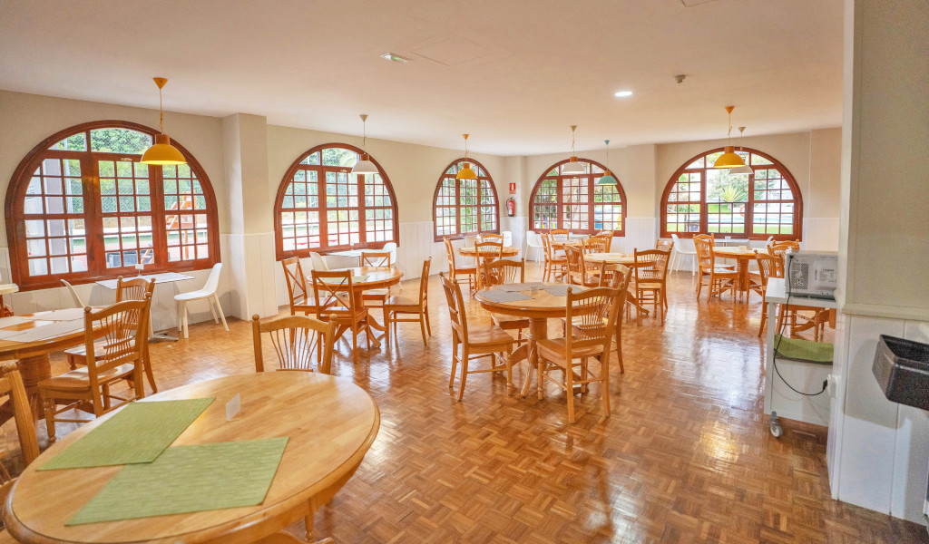 Comedor con mesas y sillas de madera junto a ventanas curvas en Tenerife.