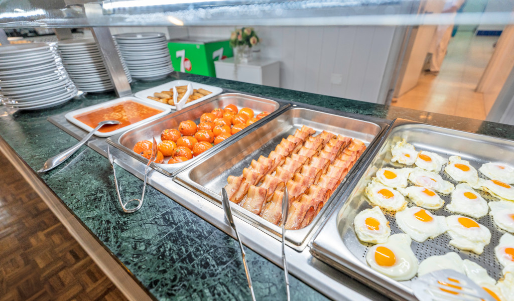 Desayuno buffet con huevos fritos, tocino, tomates y salchichas en Tenerife.