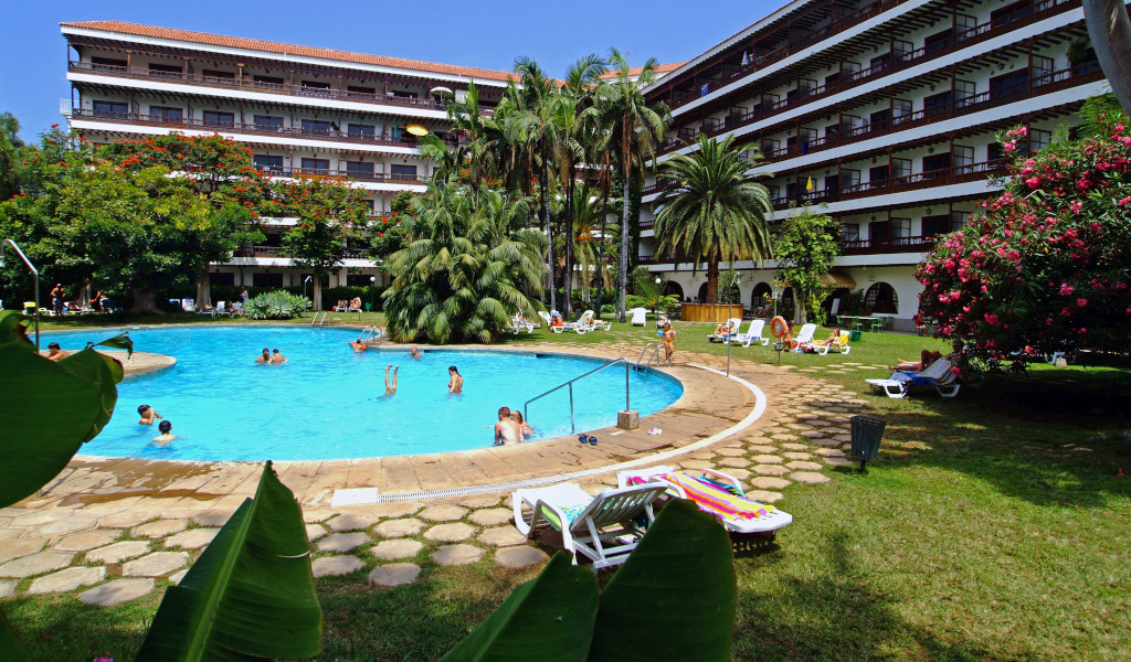 Piscina en hotel rodeada de jardines y tumbonas en Tenerife.