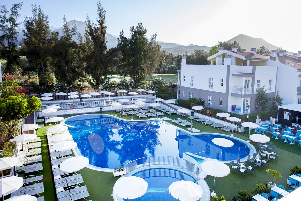Piscina y tumbonas en hotel con vista a montañas en Tenerife.