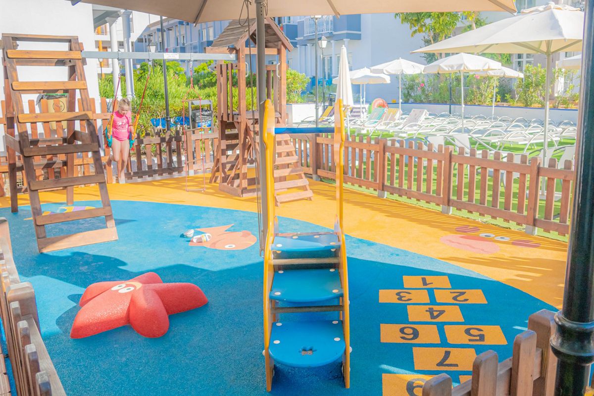 Área de juegos infantiles con columpios y tobogán en un hotel de Tenerife.