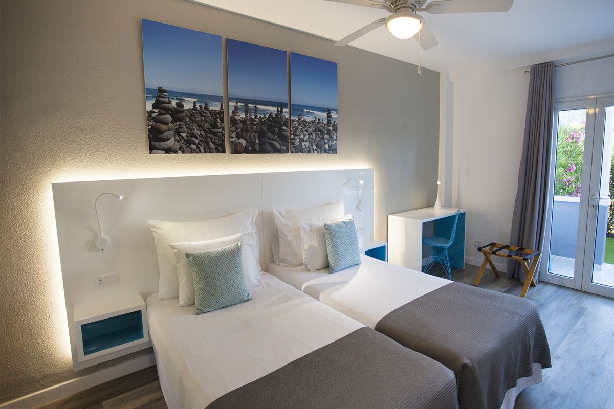 Dormitorio moderno con camas gemelas y cuadros oceánicos en Tenerife.