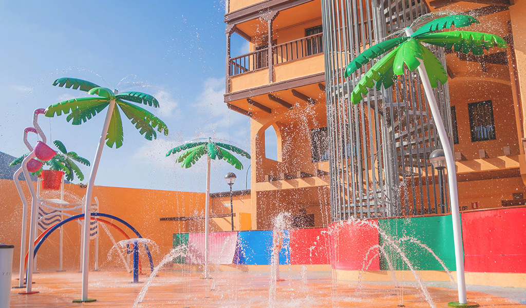 Área de juegos acuáticos con palmeras artificiales y chorros de agua en Tenerife.