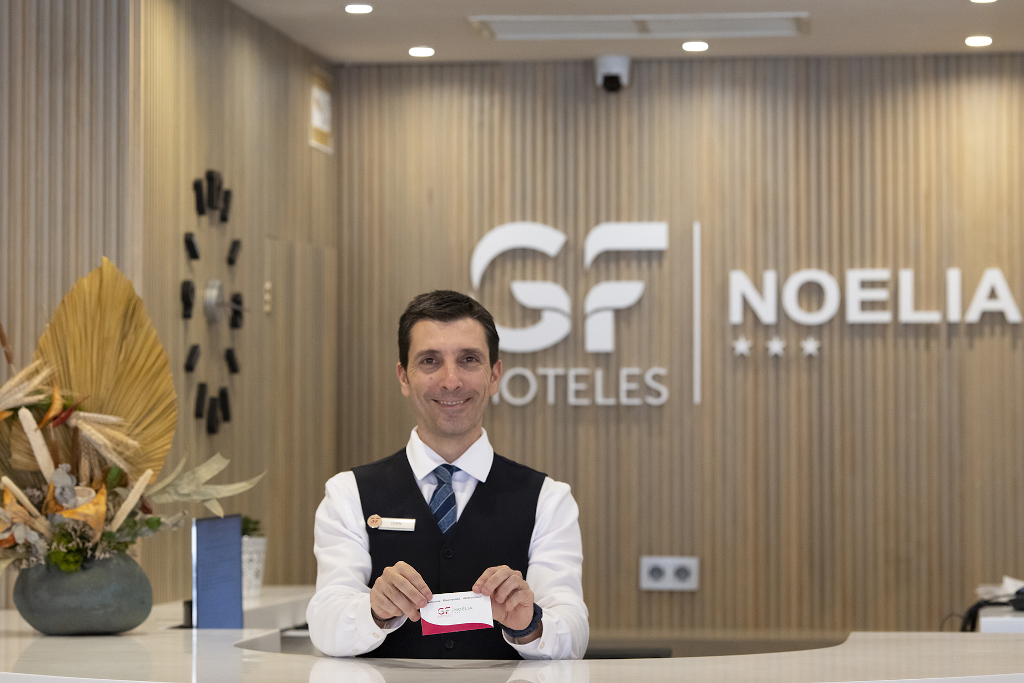 Recepcionista en GF Hoteles Noelia en Tenerife sosteniendo una tarjeta blanca.