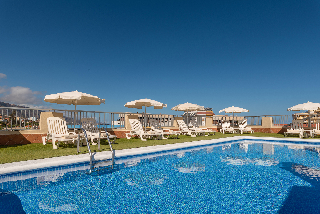 Piscina con tumbonas y sombrillas en un hotel en Tenerife.