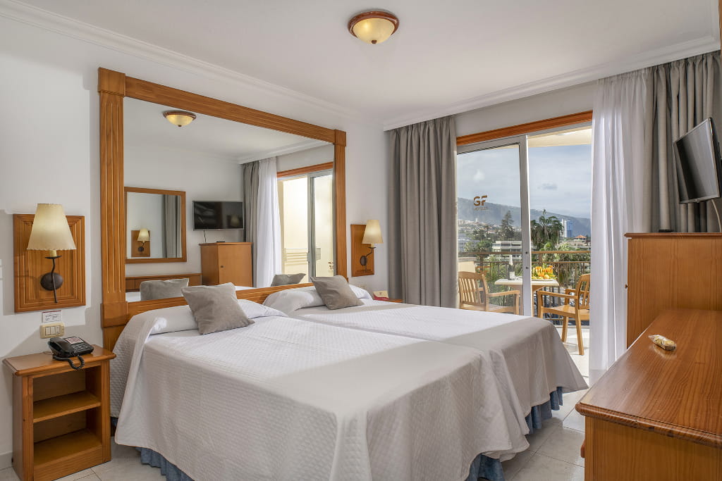 Habitación de hotel con balcón y vista hacia Puerto de la Cruz, Tenerife.