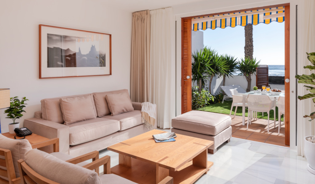 Sala de estar con salida al jardín, muebles modernos y vista al mar en Tenerife.
