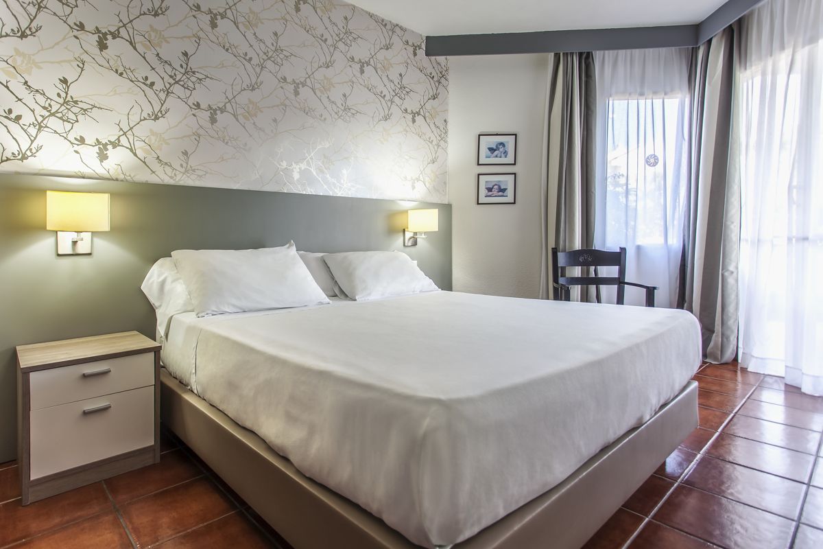 Habitación con cama grande, iluminación suave y ventanas con cortinas en Tenerife.