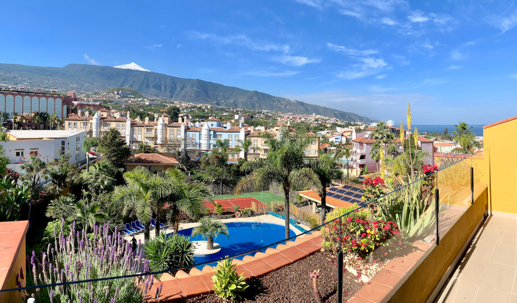 Vista de Puerto de la Cruz en Tenerife con piscina, palmeras y Teide al fondo.