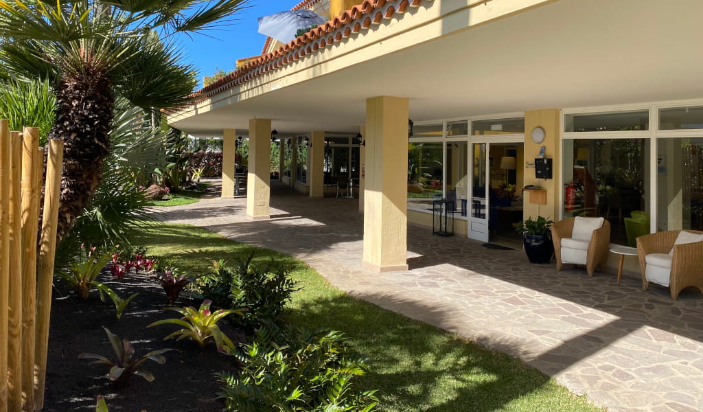 Entrada de un edificio rodeada de palmeras y jardín en Puerto de la Cruz, Tenerife.