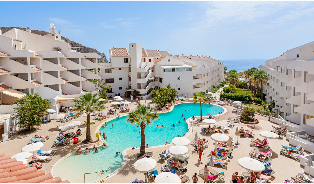Piscina en complejo turístico de Tenerife con vista al mar.