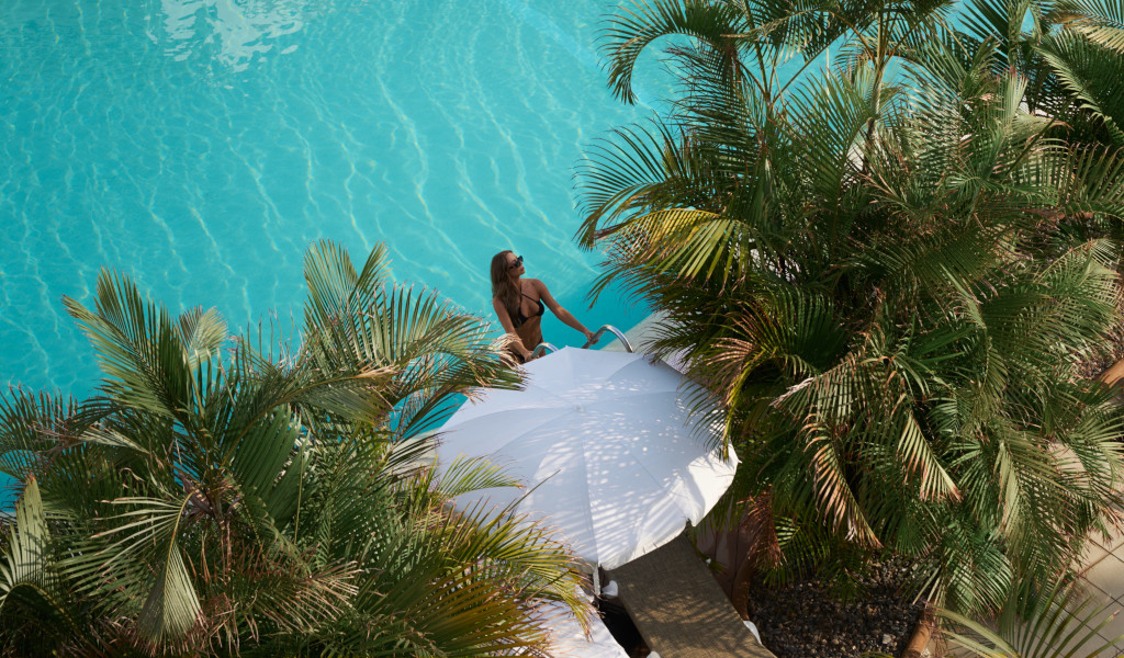 Mujer junto a piscina rodeada de palmeras en Tenerife.