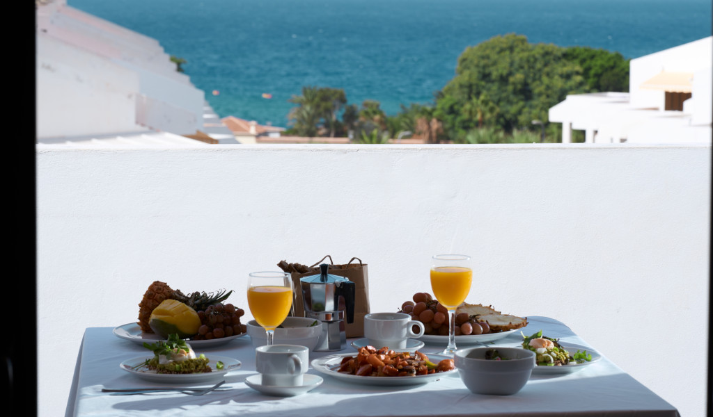 Desayuno con vistas al mar en balcón de Tenerife, con frutas y jugo de naranja.